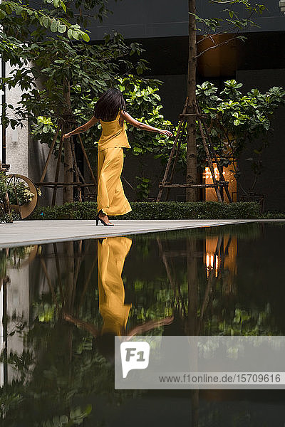 Rückenansicht einer modisch gekleideten Frau in Gelb beim Tanzen in der Stadt