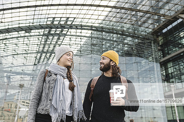 Glückliches junges Paar mit Kaffee zum Mitnehmen am Hauptbahnhof  Berlin  Deutschland
