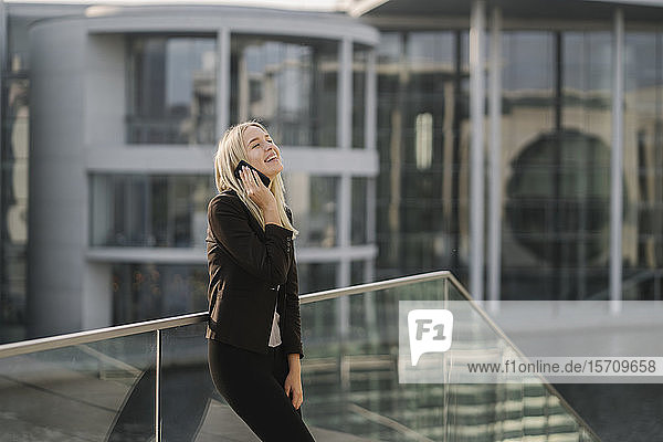 Blonde Geschäftsfrau mit Smartphone im Hintergrund modernes Gebäude