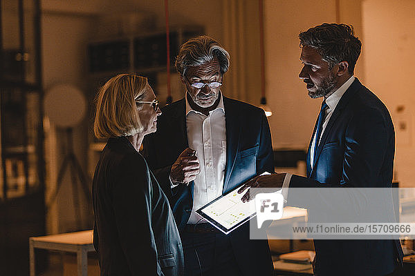 Geschäftsleute mit leuchtender Tafel sprechen im Büro