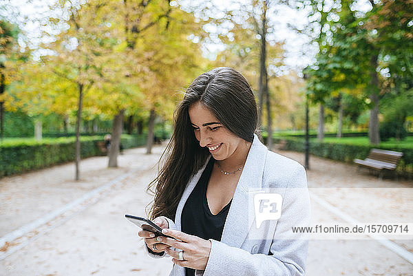 Lächelnde Frau mit Smartphone im Park