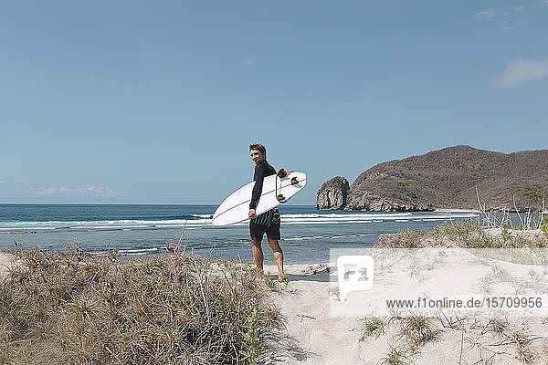 Mann mit Surfbrett am Strand  Sumbawa  Indonesien