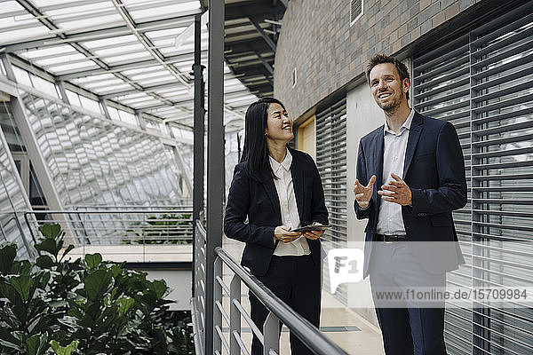 Geschäftsmann und Geschäftsfrau mit Tablett sprechend in modernem Bürogebäude