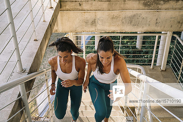 Zwei sportliche Zwillingsschwestern laufen die Treppe hinauf