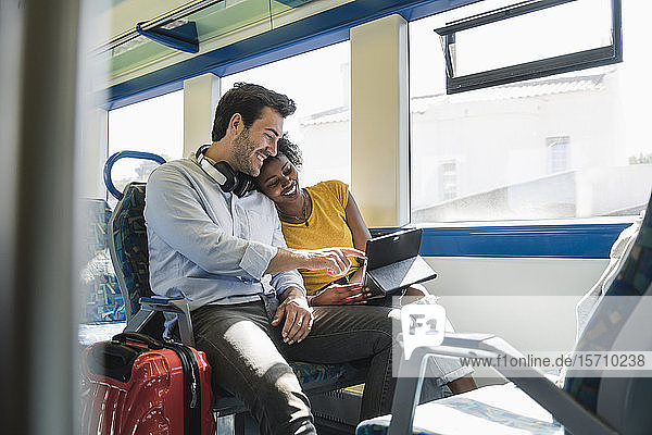 Glückliches junges Paar mit Tablette in einem Zug