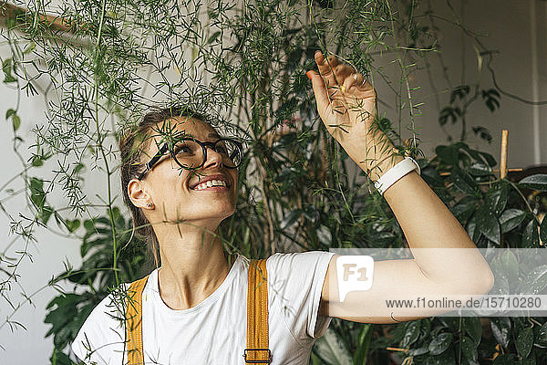 Glückliche junge Frau kümmert sich um Pflanzen