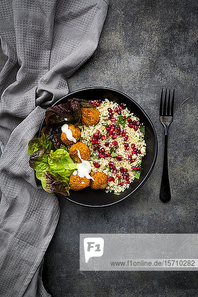 Schüssel Falafel mit Kopfsalat  Joghurt  Granatapfelkernen  Petersilie  Minze und Tabbouleh-Salat