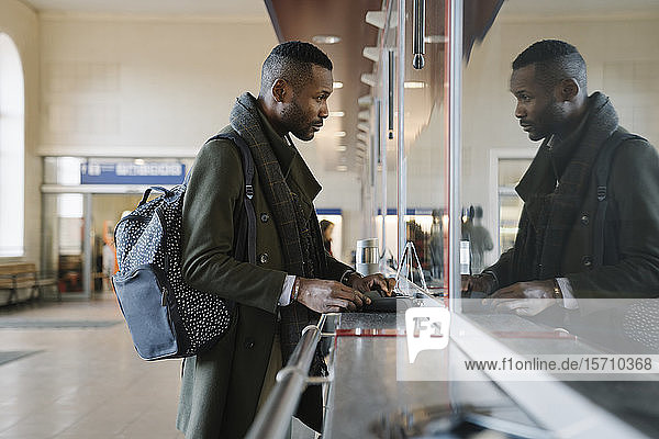 Stylish man buying ticket in train station