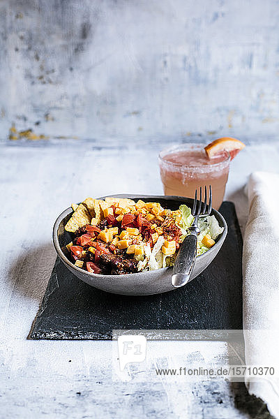 Schüssel Nachos mit Chili con Carne  Reis  Salat  Käse  Tomaten und einem Glas erfrischendem Paloma-Cocktail
