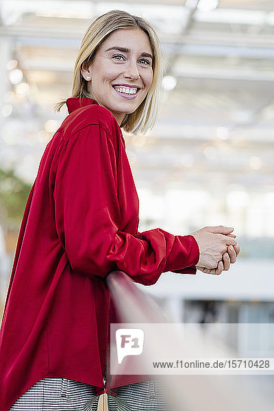 Portrait of a smiling young businesswoman standing at a railing