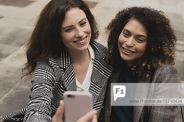 Two smiling women taking a selfie outdoors