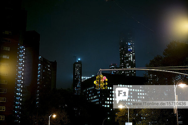 USA  New York  New York City  Stoplight hanging against illuminated skyscrapers at night