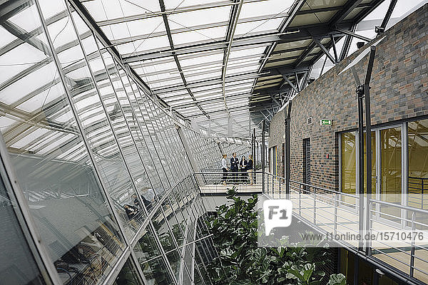 Geschäftsleute stehen auf einem Skywalk in einem modernen Bürogebäude