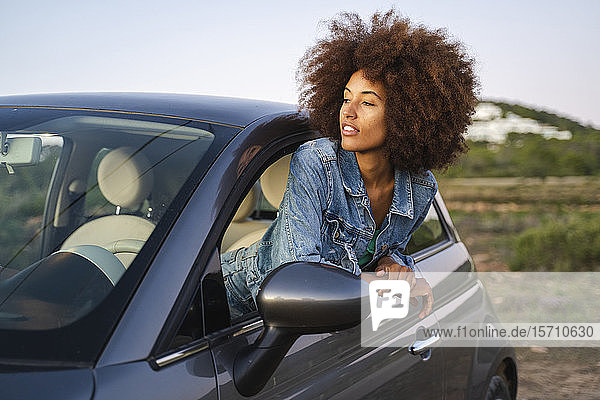 Junge Frau während einer Autofahrt  die sich aus dem Fenster lehnt