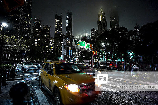 USA  New York  New York City  Verkehr auf der nächtlichen Stadtstraße mit hohen Wolkenkratzern im Hintergrund