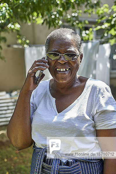 Lächelnde ältere Frau telefoniert im Freien