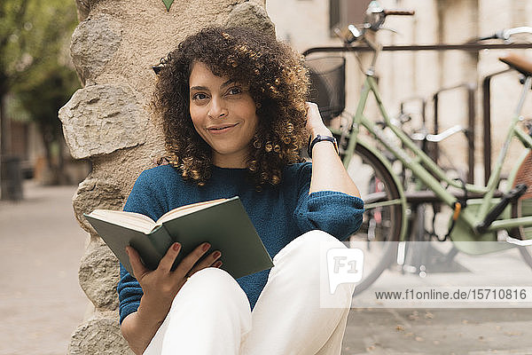 Portrait of smiling woman with a book outdoors in the city