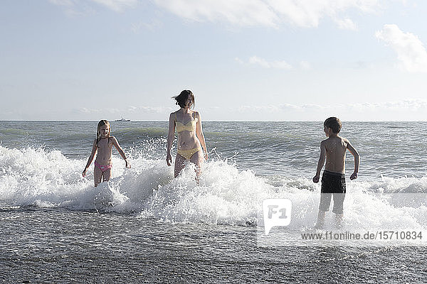 Glückliche Mutter mit zwei Kindern  die sich im Meer vergnügen