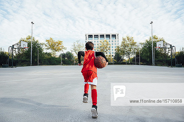 Boy playing basketball on outdoor court