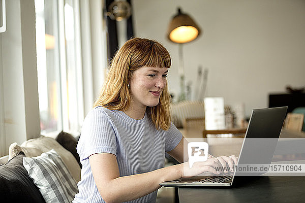 Porträt einer erdbeerblonden jungen Frau mit Nasenpiercing mit Laptop in einem Café