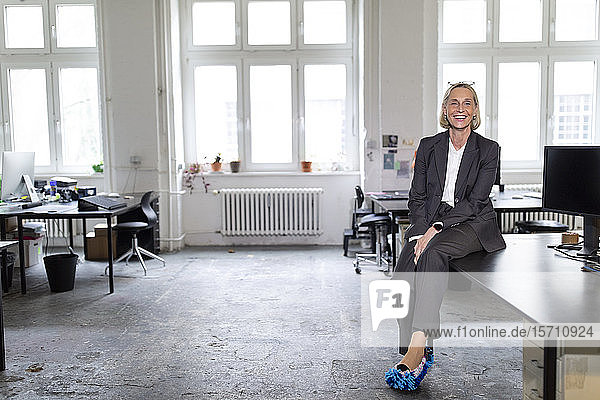 Happy mature businesswoman wearing cleansing slippers in office