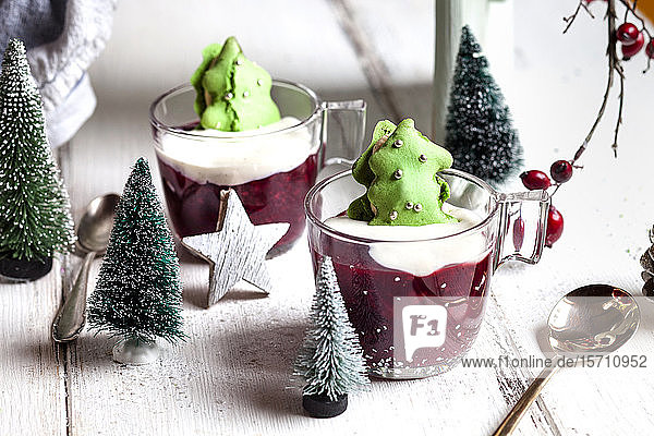 Tassen mit rotem Brei und grünen Makronen-Weihnachtsbäumen