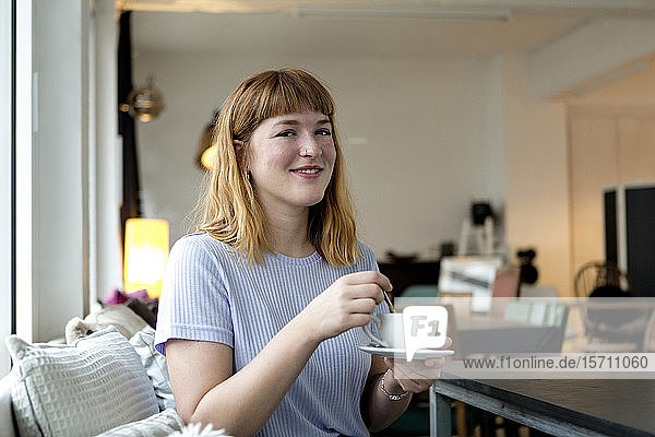Porträt einer erdbeerblonden jungen Frau mit Nasenpiercing bei einer Tasse Kaffee in einem Cafe
