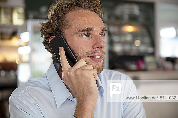 Junger Geschäftsmann telefoniert in einem Cafe