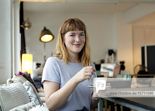 Portrait of strawberry blonde young woman with nose piercing with cup of coffee in a cafe