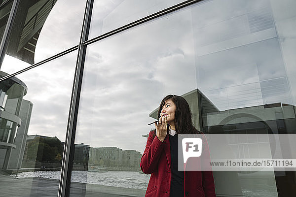 Geschäftsfrau  die in der Nähe eines modernen Gebäudes steht und ein Smartphone benutzt