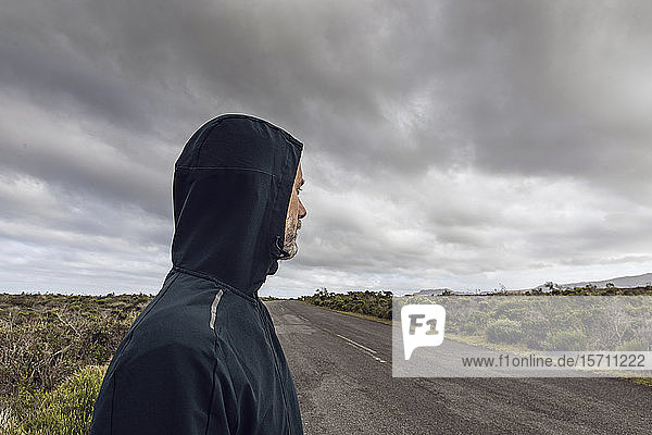 Man in rural scene wearing hooded jacket looking at distance  Cape Point  Western Cape  South Africa