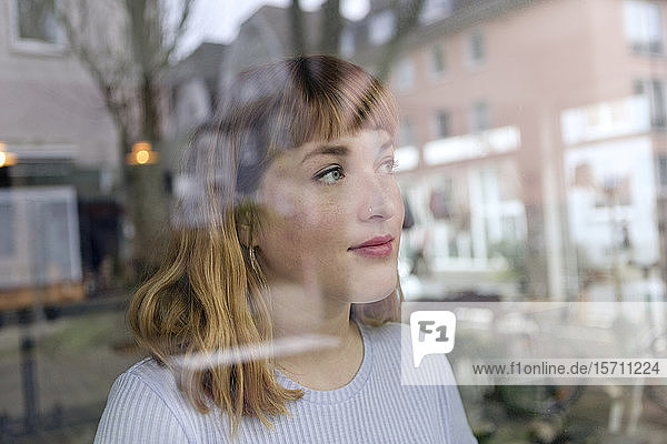 Porträt einer jungen Frau mit Nasenpiercing  die aus dem Fenster schaut