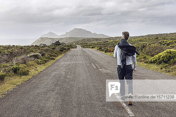 Back view of businessman walking on country road  Cape Point  Western Cape  South Africa