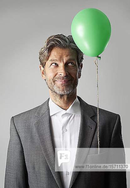 Porträt eines lächelnden Geschäftsmannes mit grünem Ballon