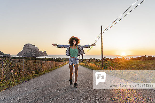 Junge Frau steht bei Sonnenuntergang auf der Straße  Ibiza