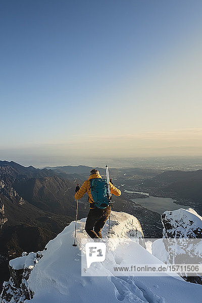 Mountaineer reaching the top of a snowy mountain enjoying the view  Lecco  Italy