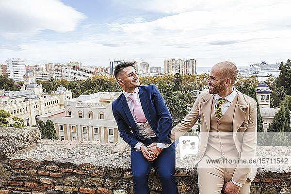 Elegant gay couple holding hands at an observation point above the city  Malaga  Spain