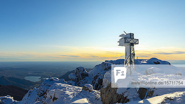 View over snowy mountains with a frozen summit cross  Lecco  Italy