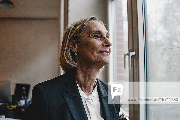 Mature businesswoman looking out of window in office