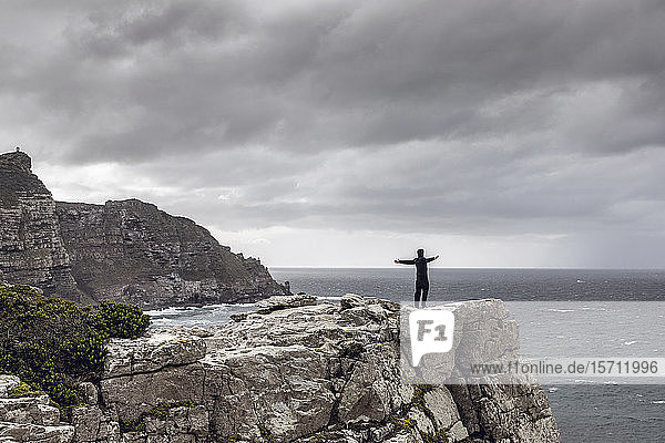 Man standing on rocky cliff looking at horizon  Cape Point  Western Cape  South Africa