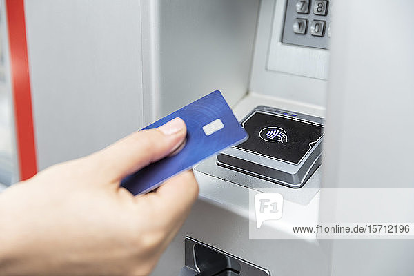 Nahaufnahme einer Hand  die eine Kreditkarte hält und kontaktlos bezahlt