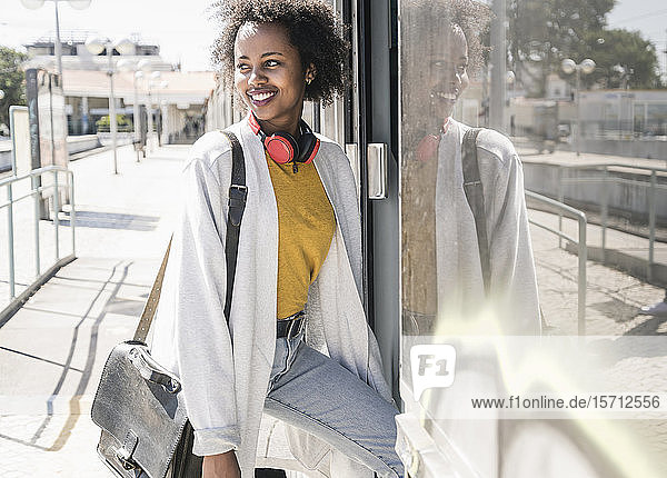 Smiling young woman entering a train