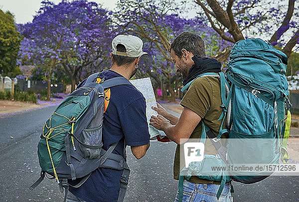 Zwei Rucksacktouristen überprüfen eine Karte auf einer Straße