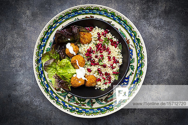 Schüssel Falafel mit Kopfsalat  Joghurt  Granatapfelkernen  Petersilie  Minze und Tabbouleh-Salat