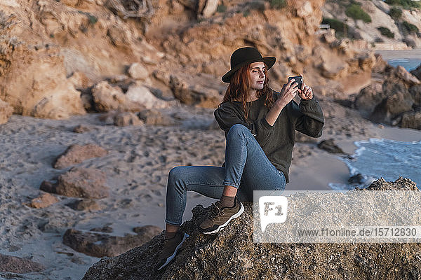 Junge Frau benutzt Smartphone am Strand bei Sonnenuntergang  Ibiza