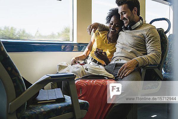 Junges Paar mit Smartphone entspannt sich in einem Zug