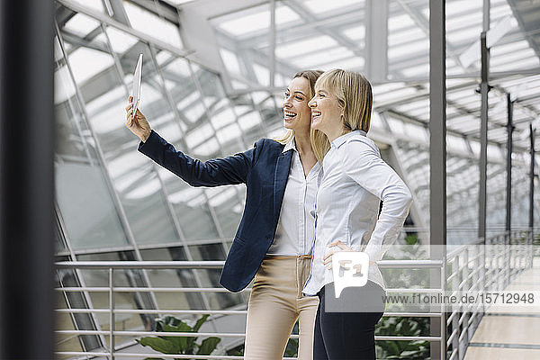 Two happy young businesswomen using a tablet in office