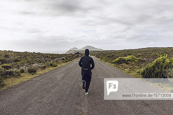 Back view of man jogging on country road  Cape Point  Western Cape  South Africa