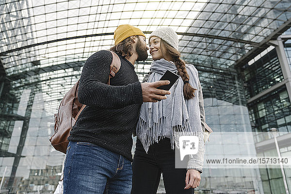 Liebevolles junges Paar mit Smartphone am Hauptbahnhof  Berlin  Deutschland