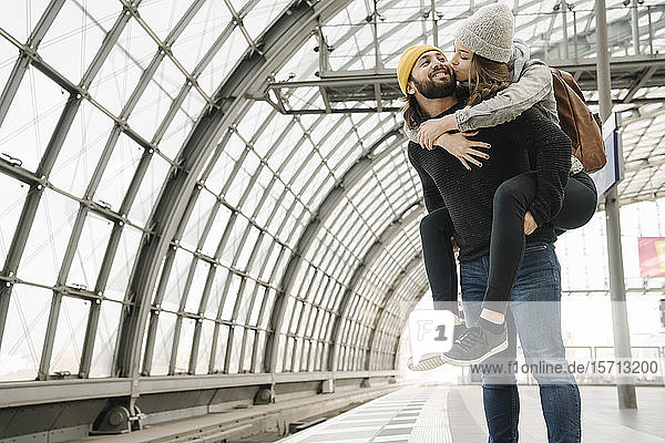 Glückliches junges Paar mit Spaß und Küssen auf dem Bahnsteig  Berlin  Deutschland